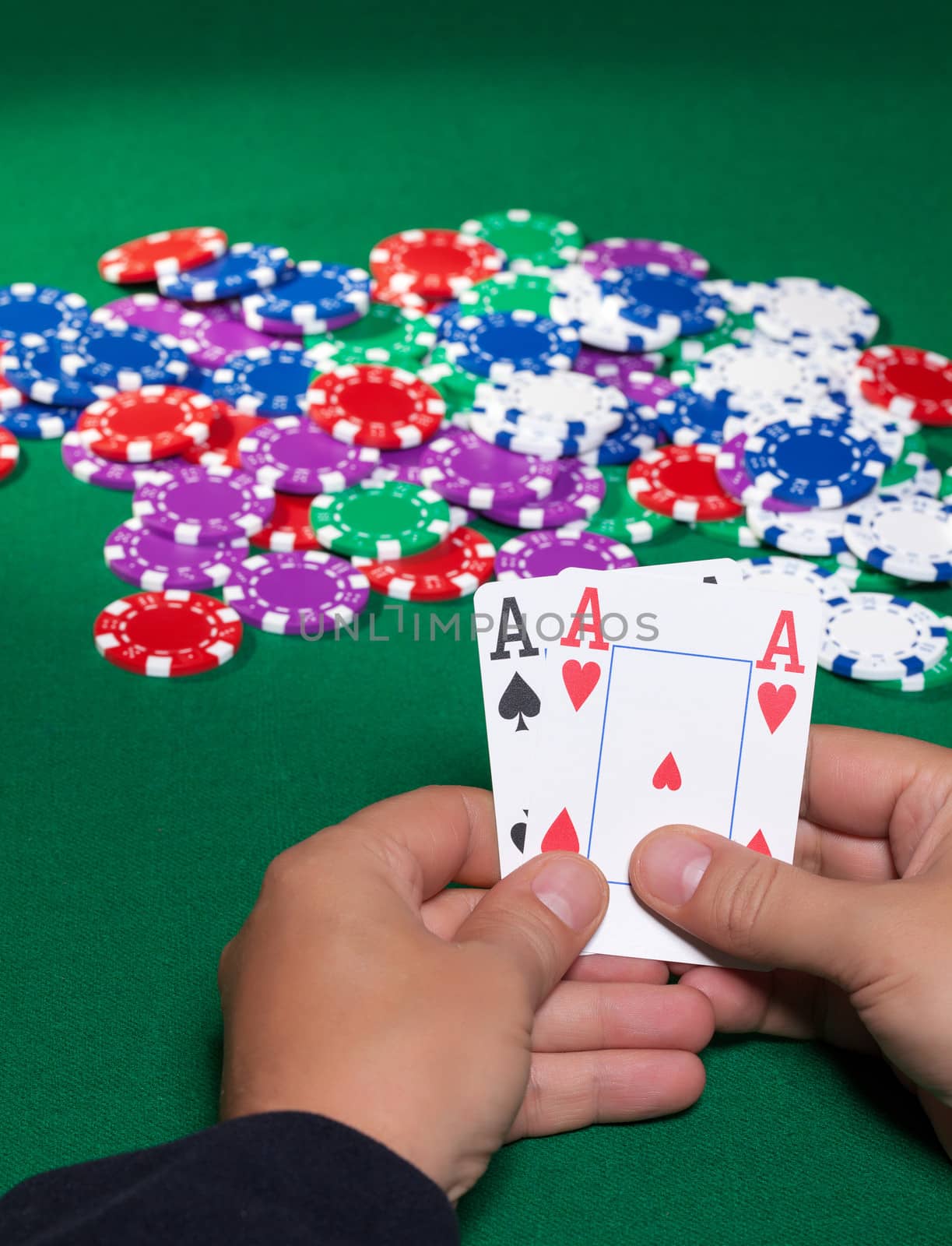 Colorful poker chips and two Ace closeup on green cloth