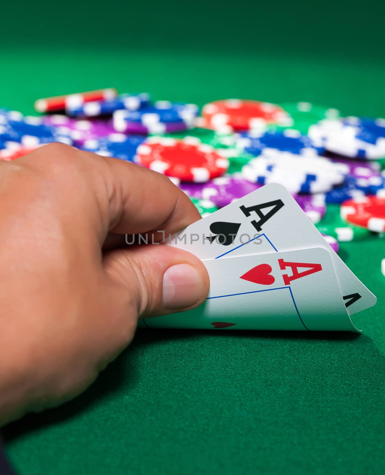 Colorful poker chips and two Ace closeup on green cloth