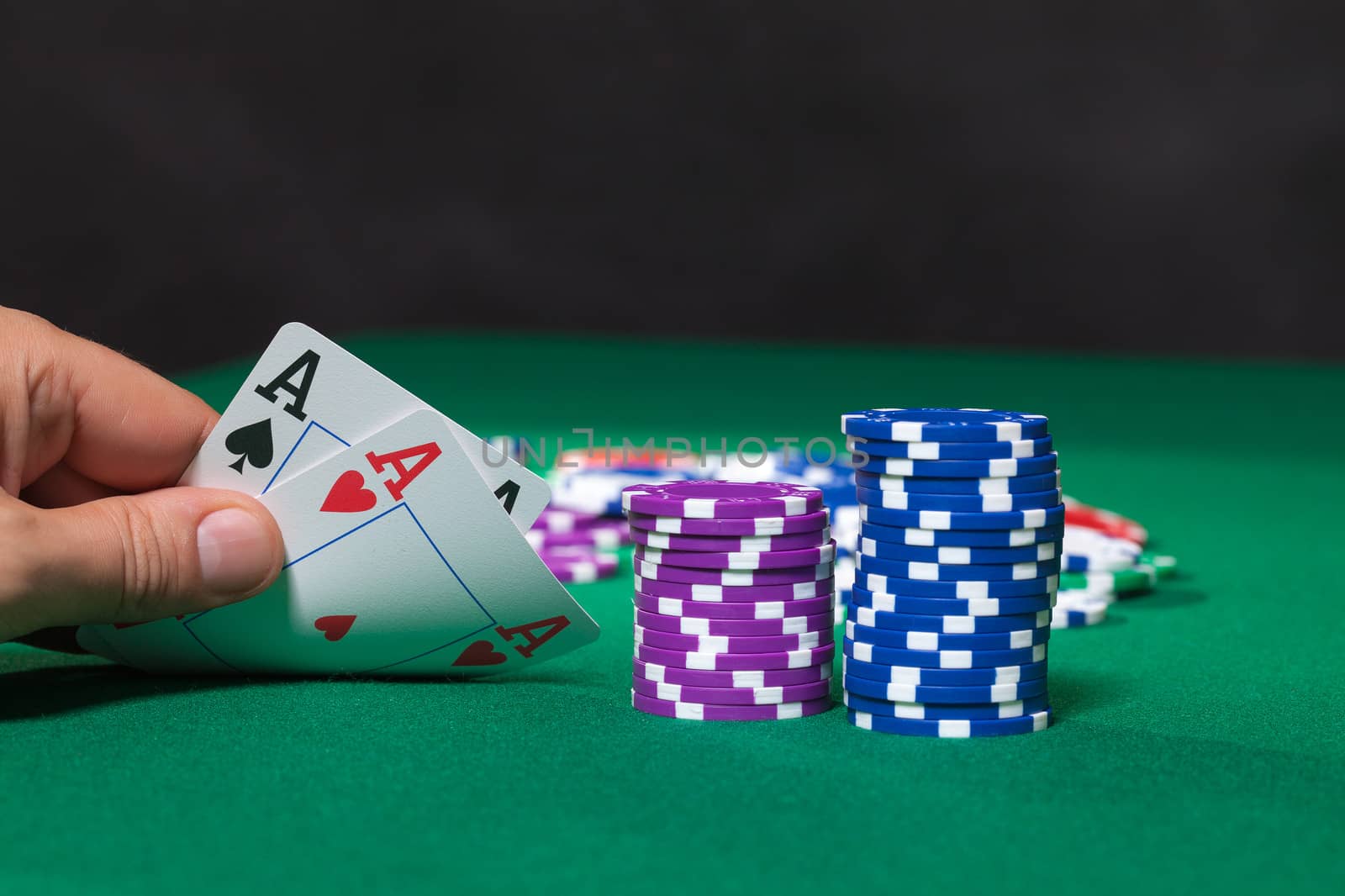 Colorful poker chips and two Ace closeup on green cloth