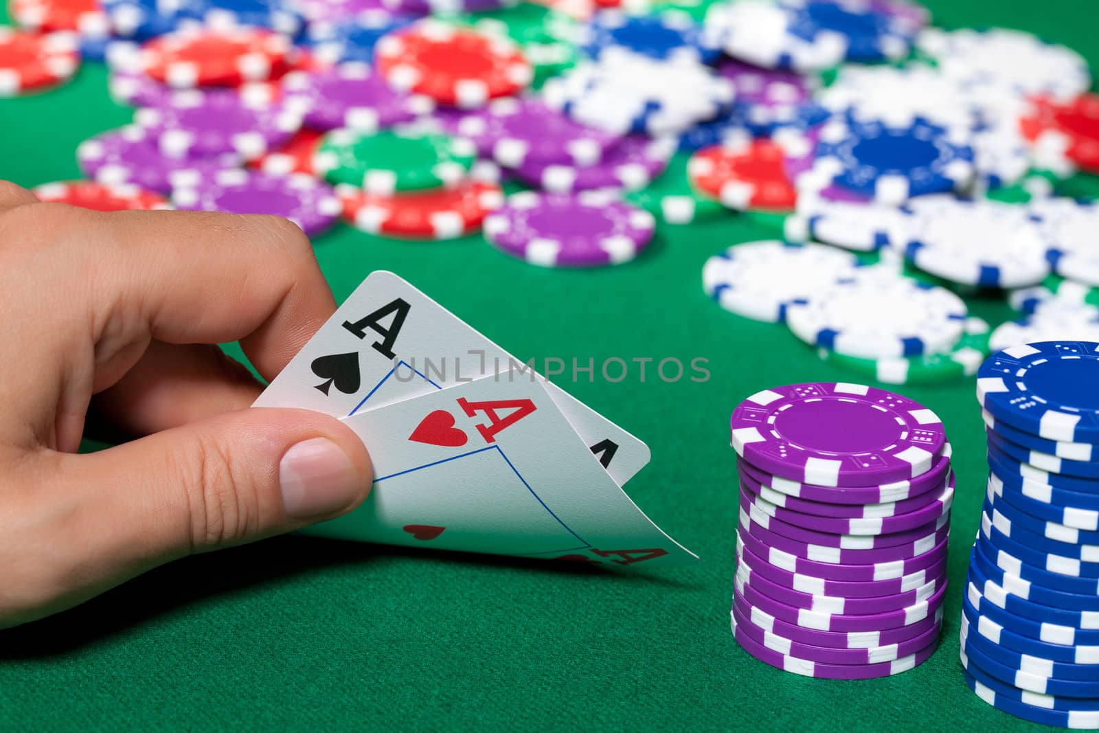 Colorful poker chips and two Ace closeup on green cloth