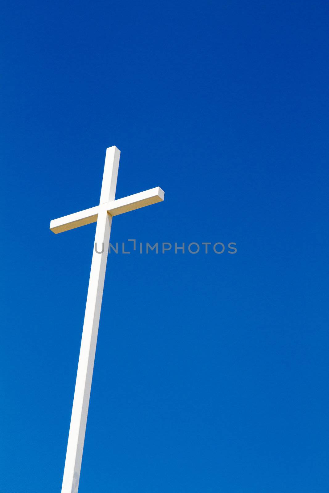 Christian cross made of steel against a background of blue sky.