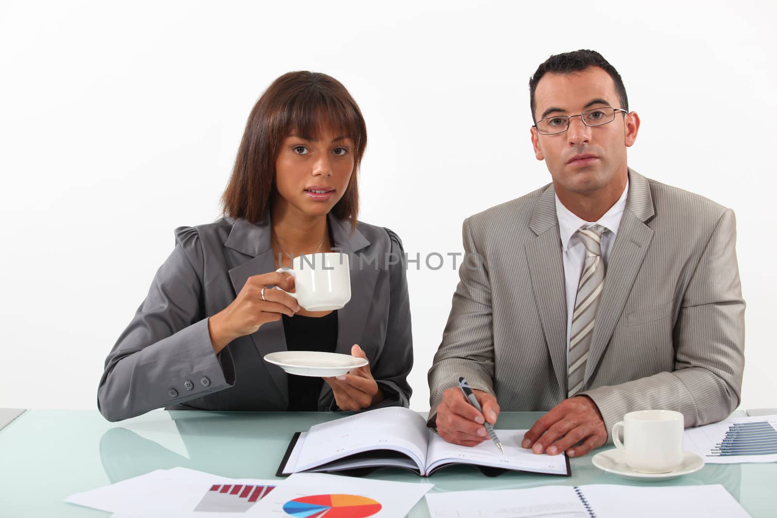 businessman and businesswoman examining a project and drinking coffee by phovoir