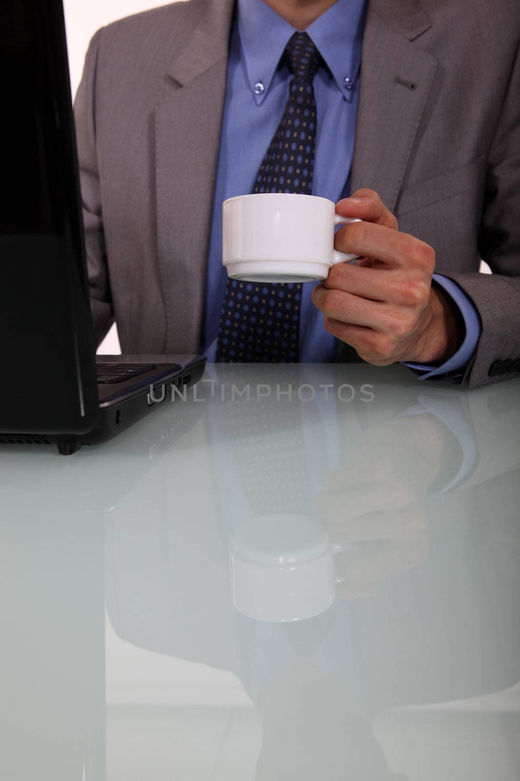 Businessman with a coffee and a laptop by phovoir