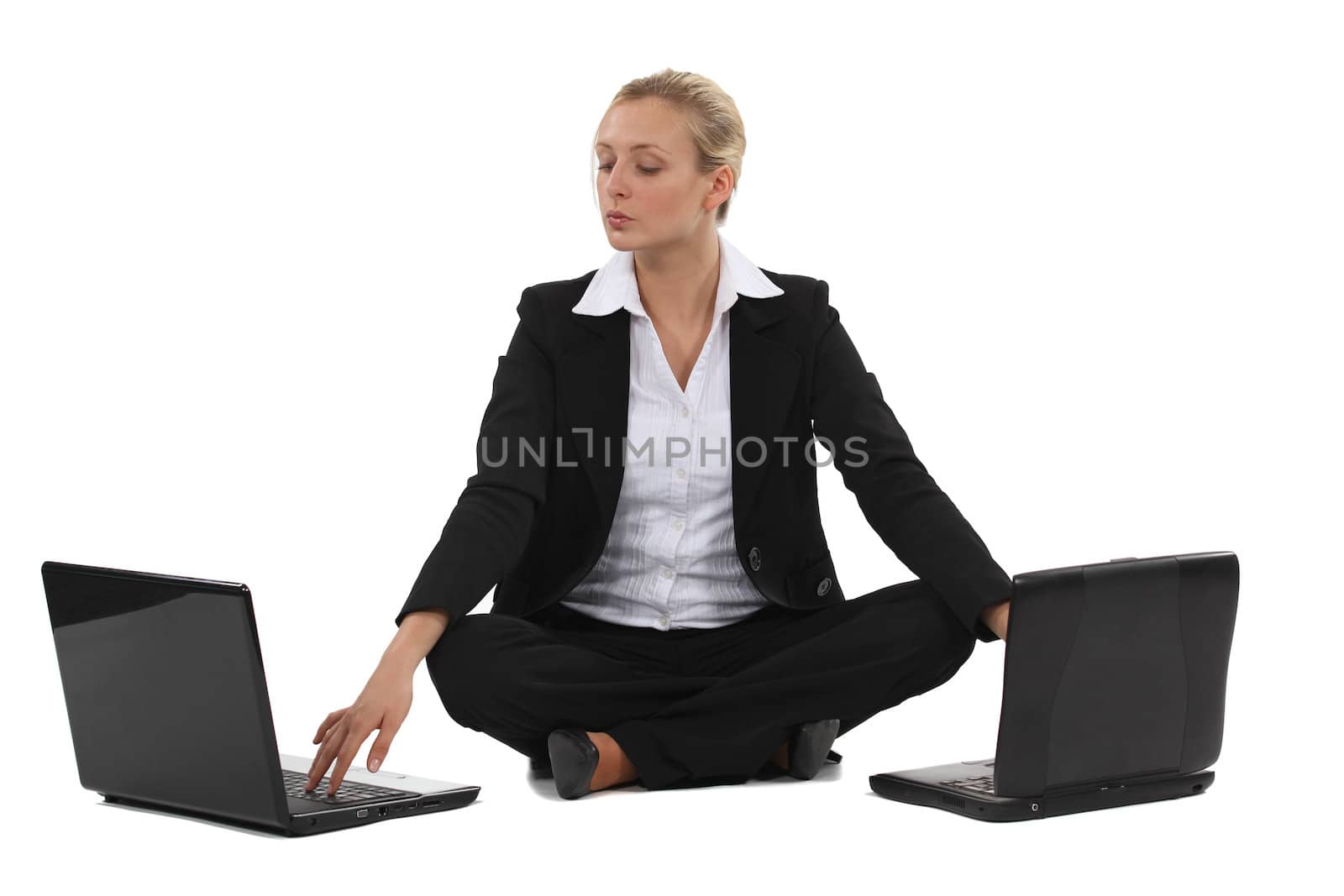 Blond businesswoman sat with two laptops by phovoir
