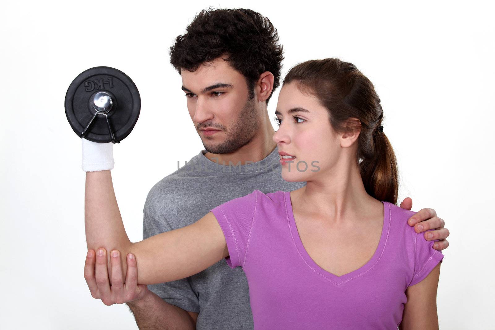 Coach helping a client lift a dumbbell