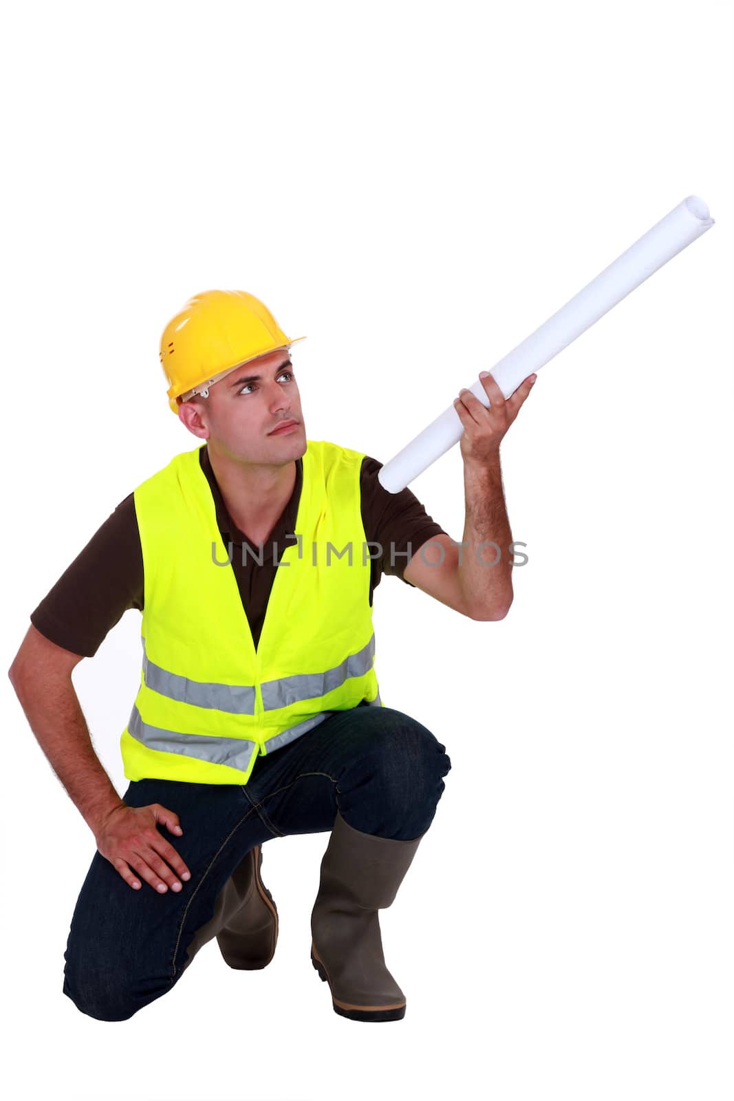 Tradesman holding up a rolled-up blueprint by phovoir