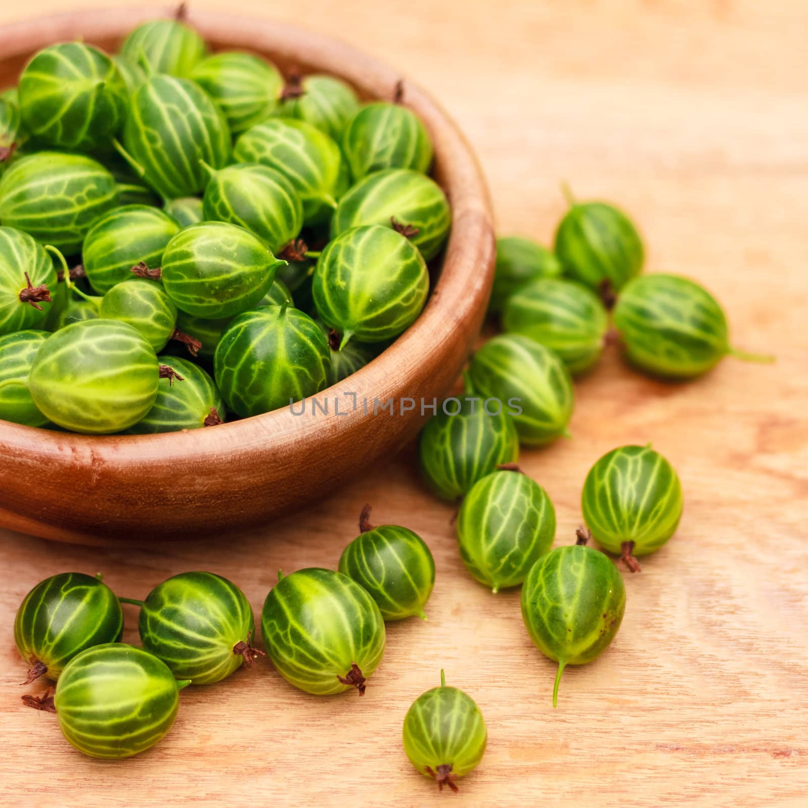 Old Wooden Bowl Filled With Succulent Juicy Fresh Ripe Green Gooseberries On An Old Wooden Table Top.