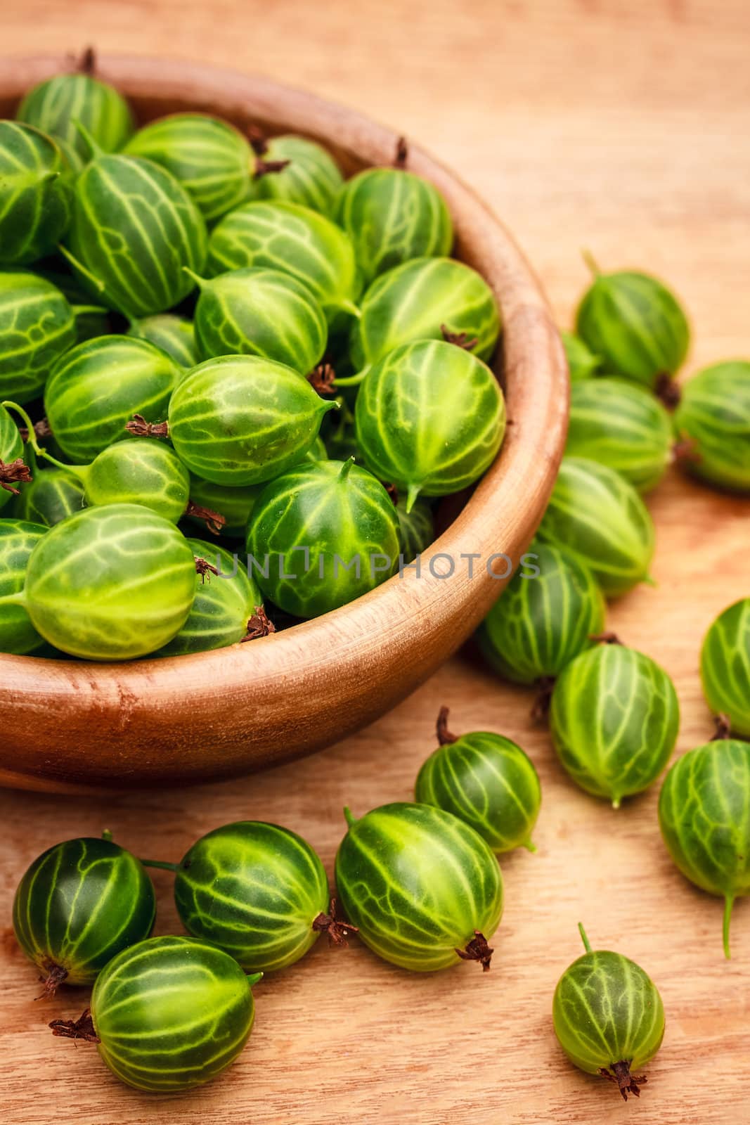 Close-Up Of Gooseberries In Vintage Wooden Bowl On Wooden Table by ryhor