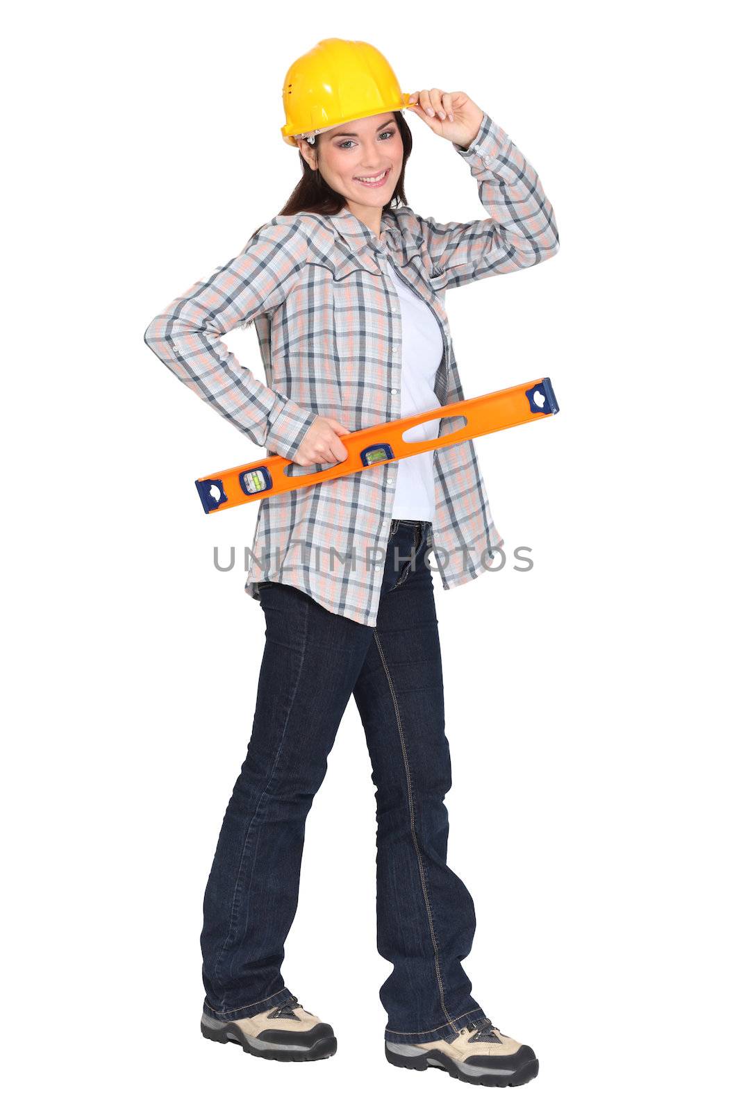 female carpenter holding ruler with hand to hard hat by phovoir