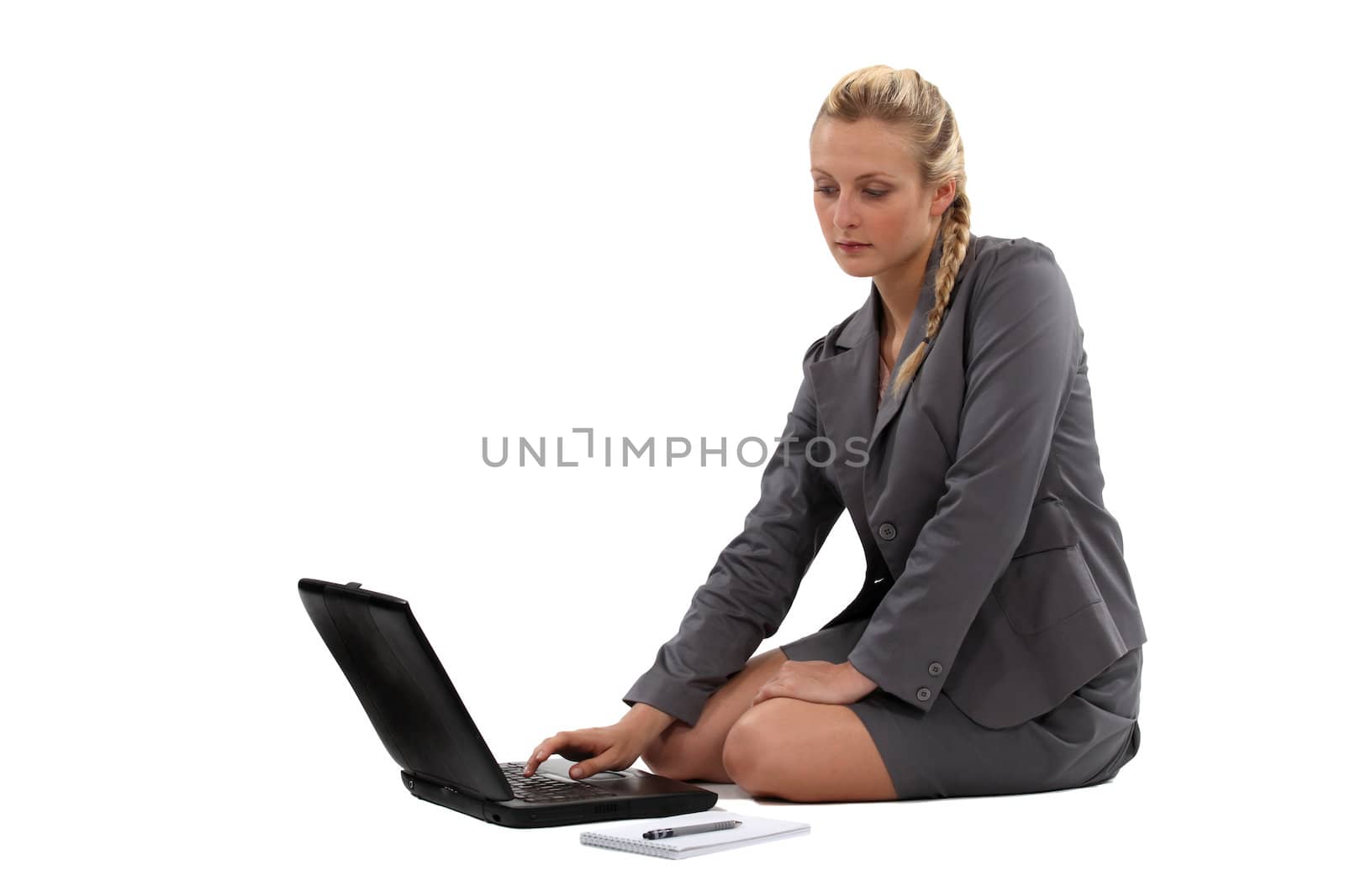 Businesswoman sitting on the floor with her laptop by phovoir