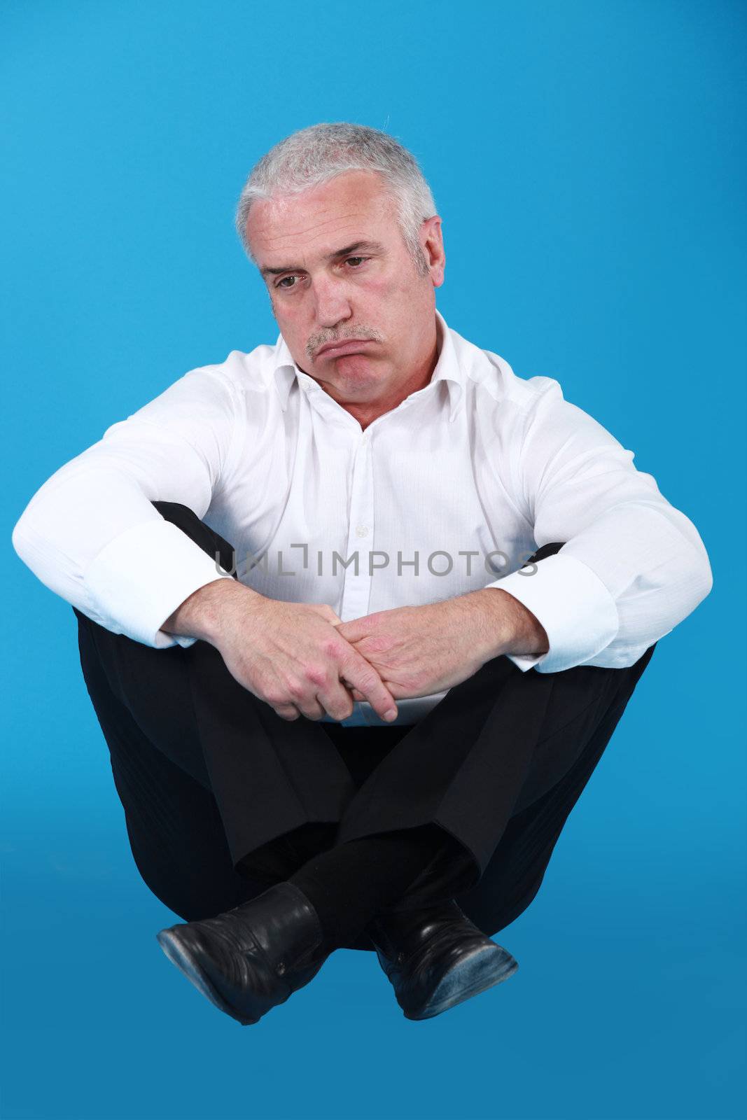 senior man in a suit looking sad by phovoir