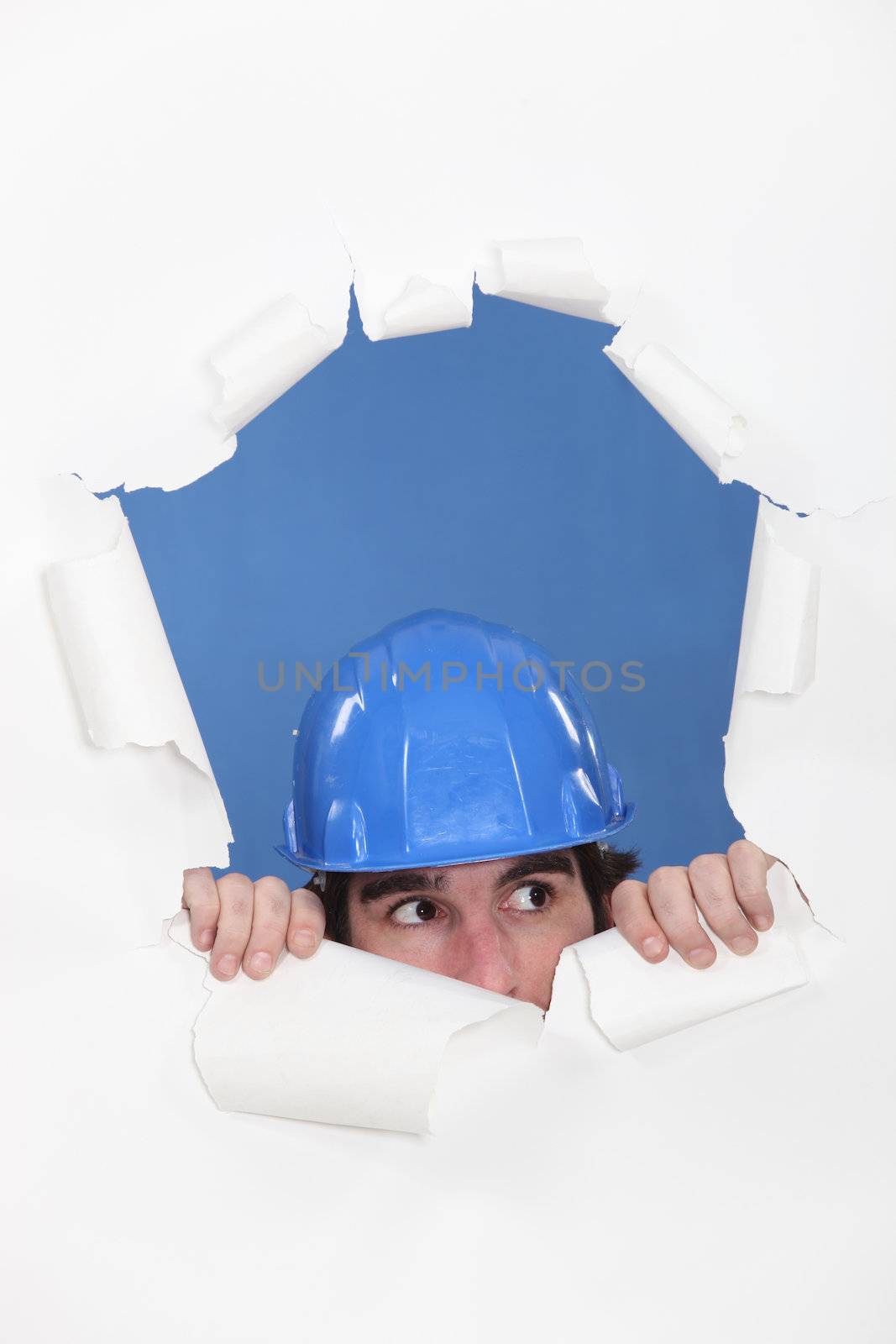 Tradesman peeking out through an opening in a wall