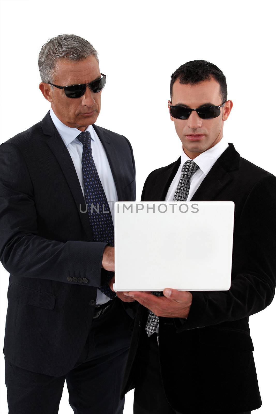 Businessmen wearing sunglasses and looking at a laptop