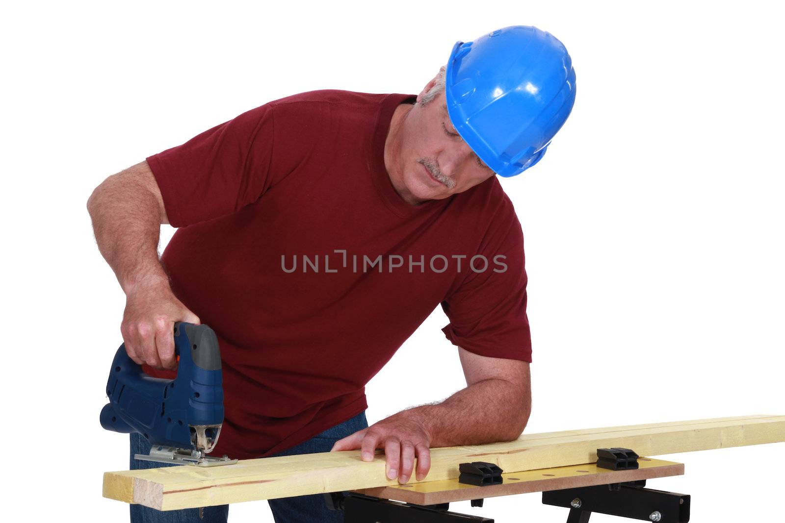 A male carpenter using a jigsaw. by phovoir