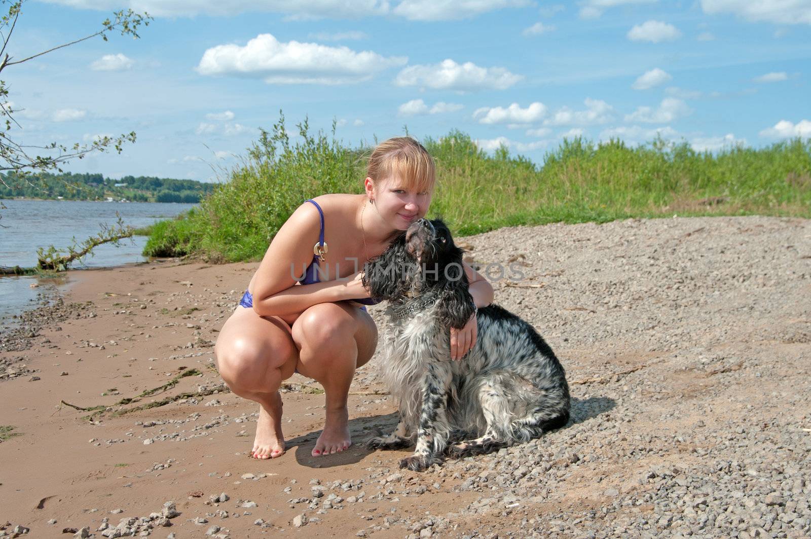 Blonde with a spaniel on the river bank.