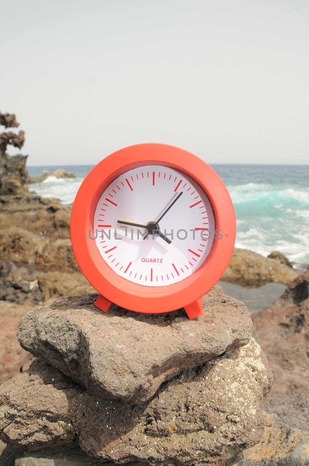 One Red Clock on the Rocks Near the Ocean 