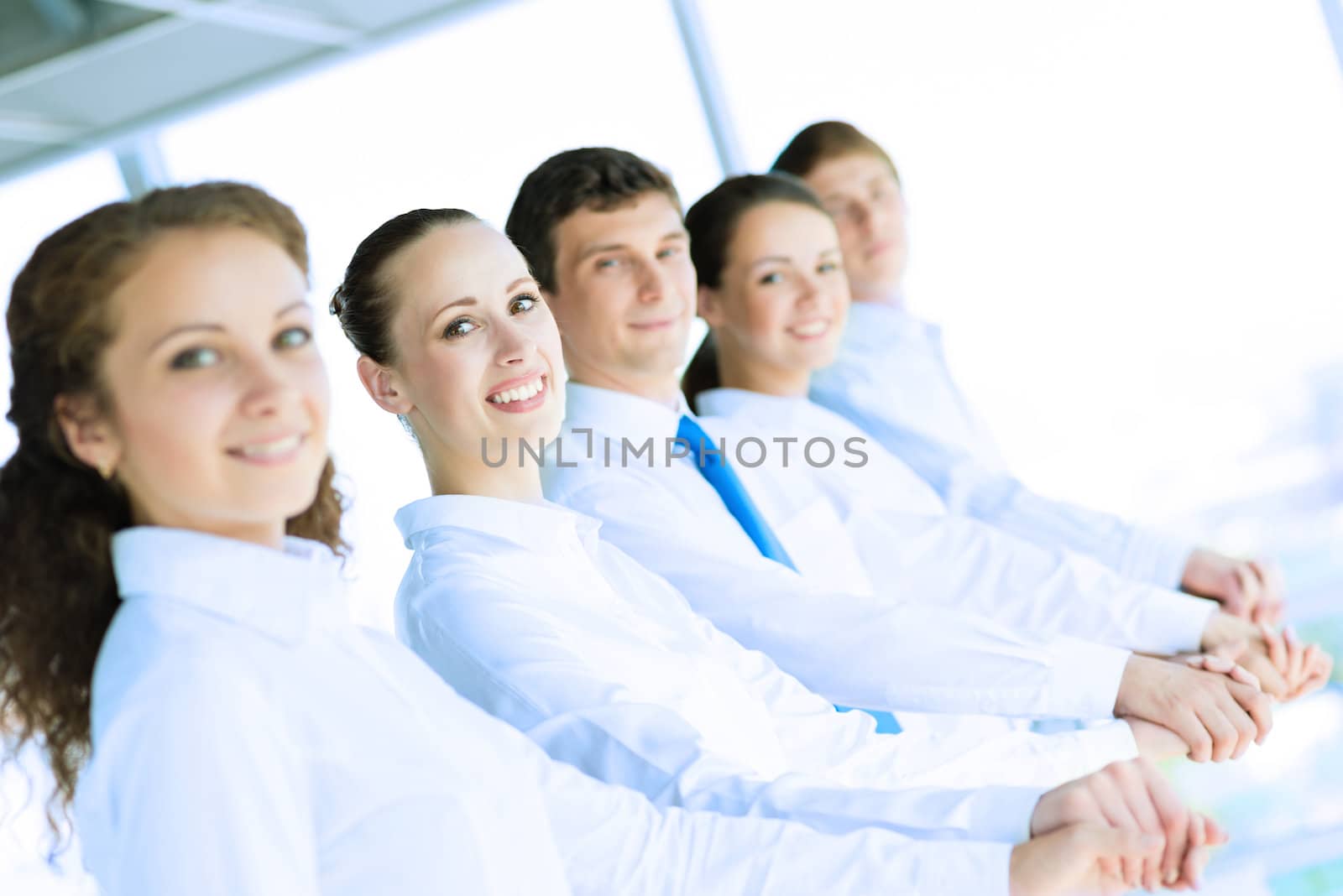 young business people holding hands, standing in a row, the concept of teamwork