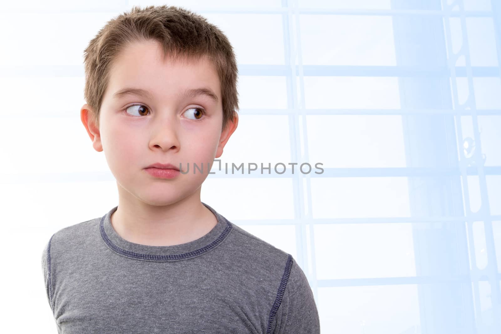 Eight years old kid looking out skeptically accusing with his big eyes