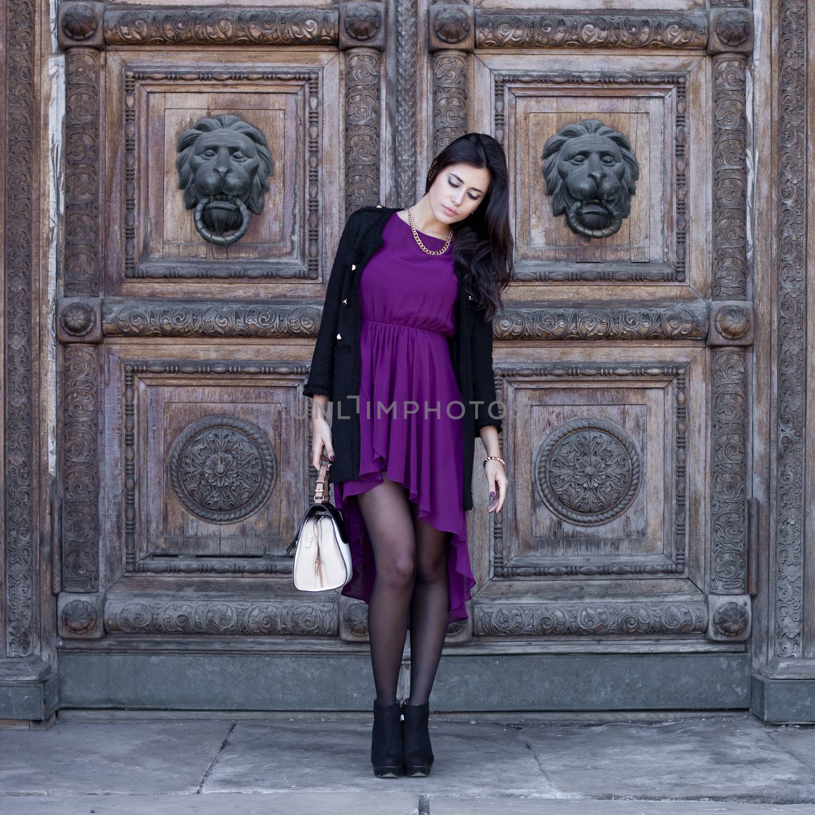 Young beautiful woman in a burgundy dress on a background of wooden gates