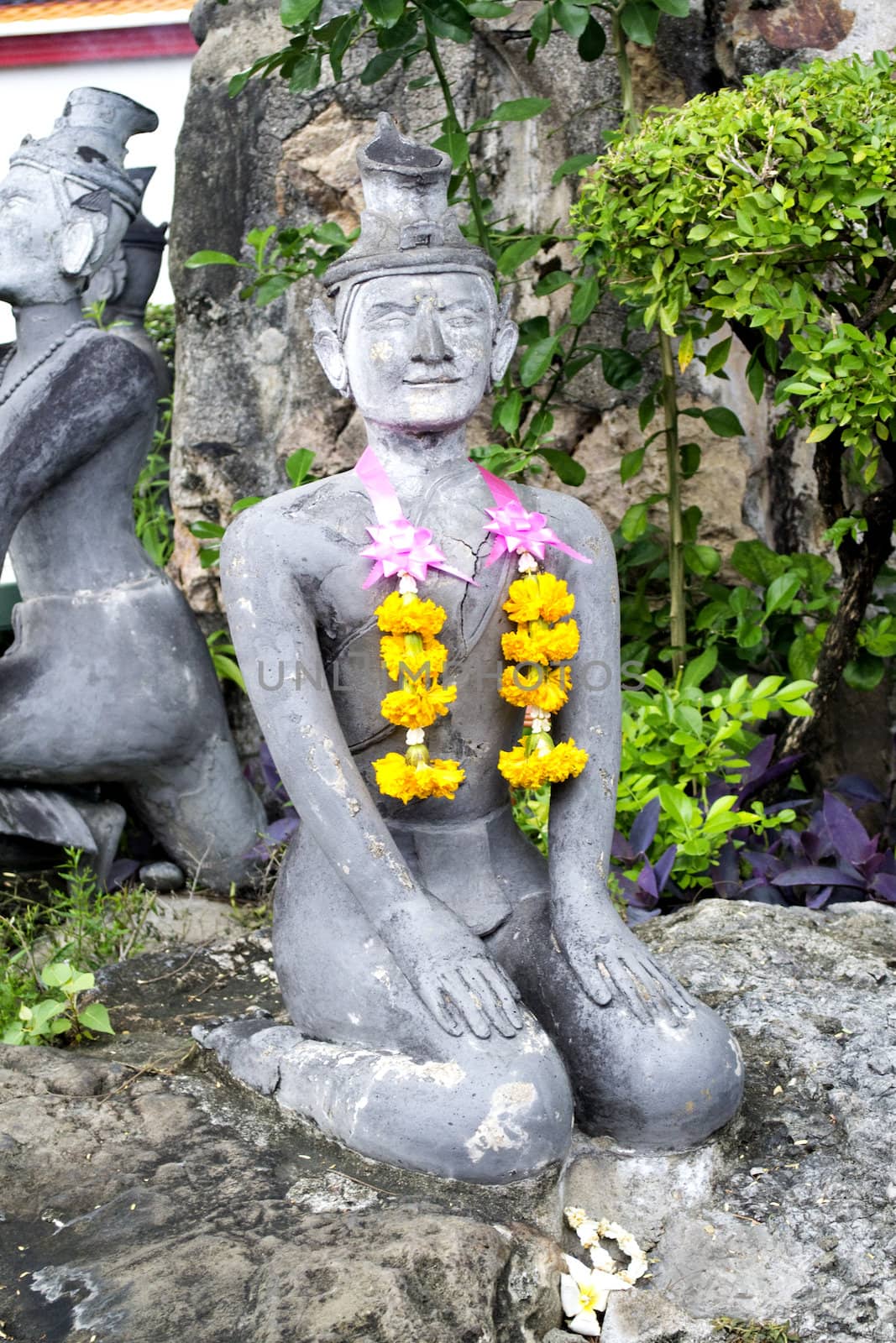 Thai Buddha stone stateue with flower garmet