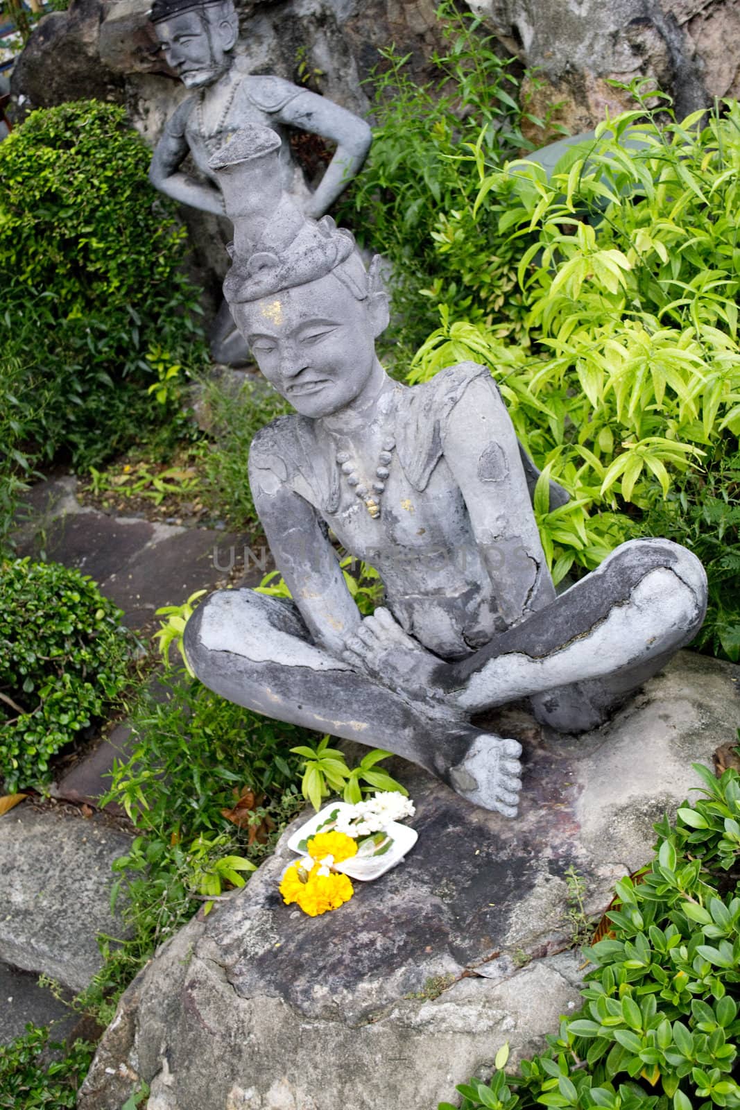 Thai Buddha stone stateue with flower garmet