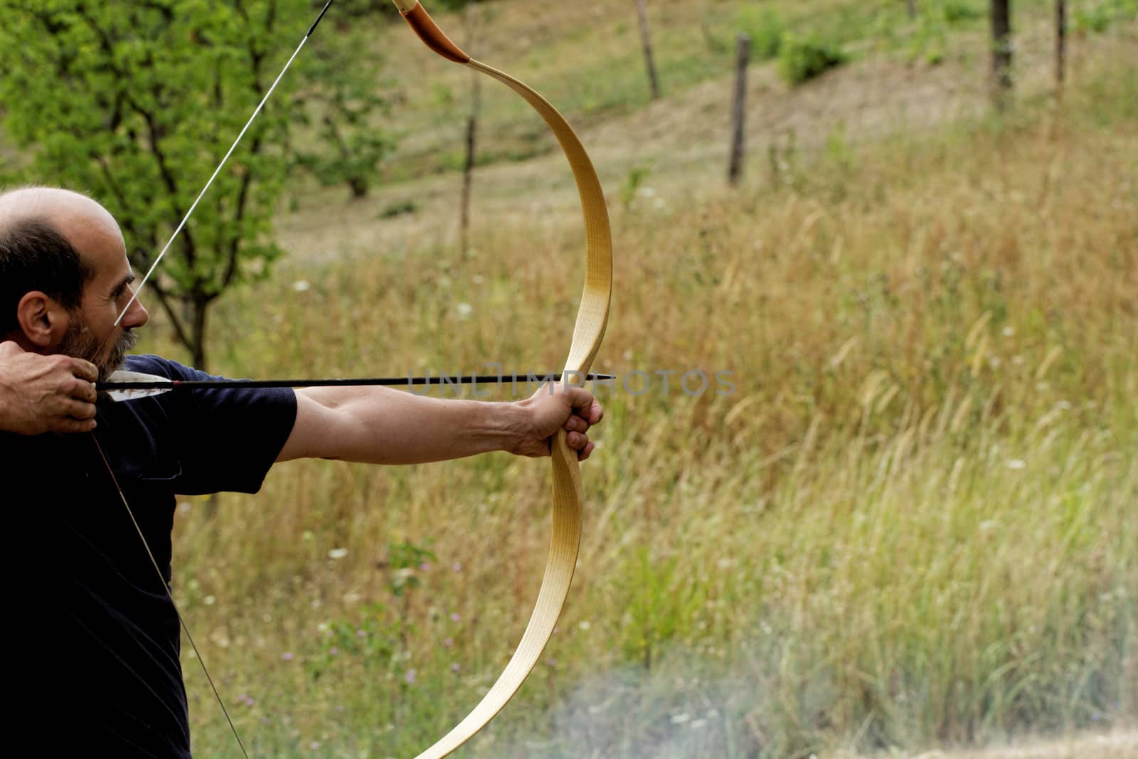 archery man shooting arrow with bow in the nature