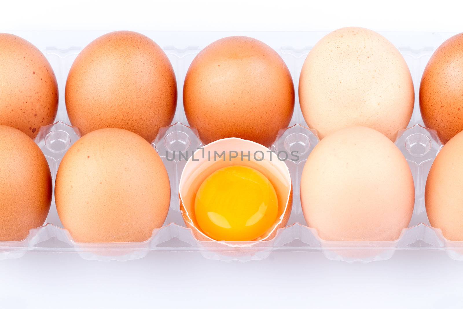 Eggs and yolk in a plastic transparent package on white background