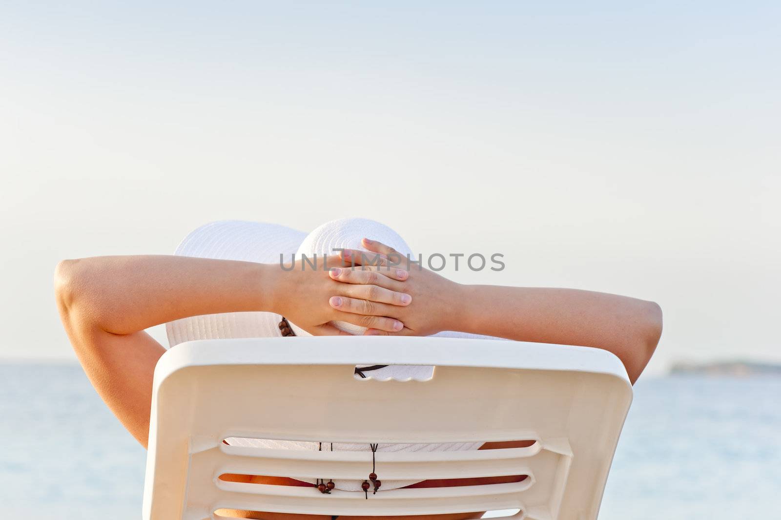 woman on vacation at the beach in a lounge chair by kosmsos111