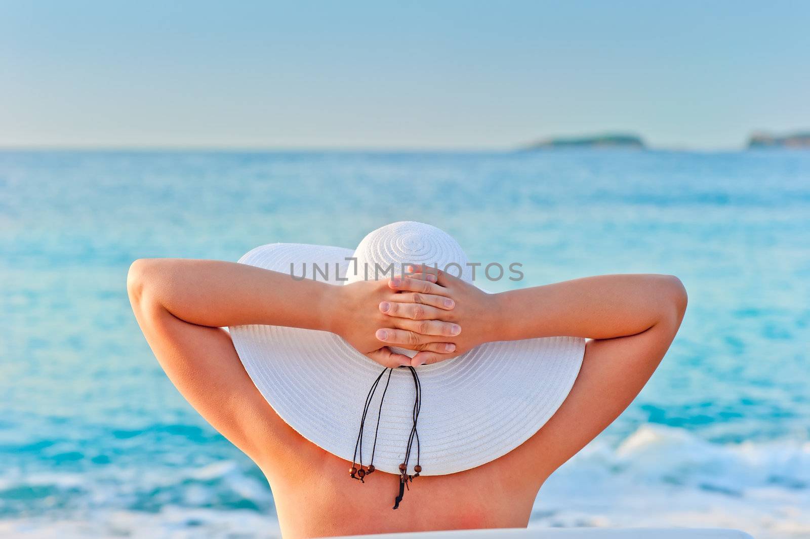 woman takes a sunbath in white hat near the sea by kosmsos111