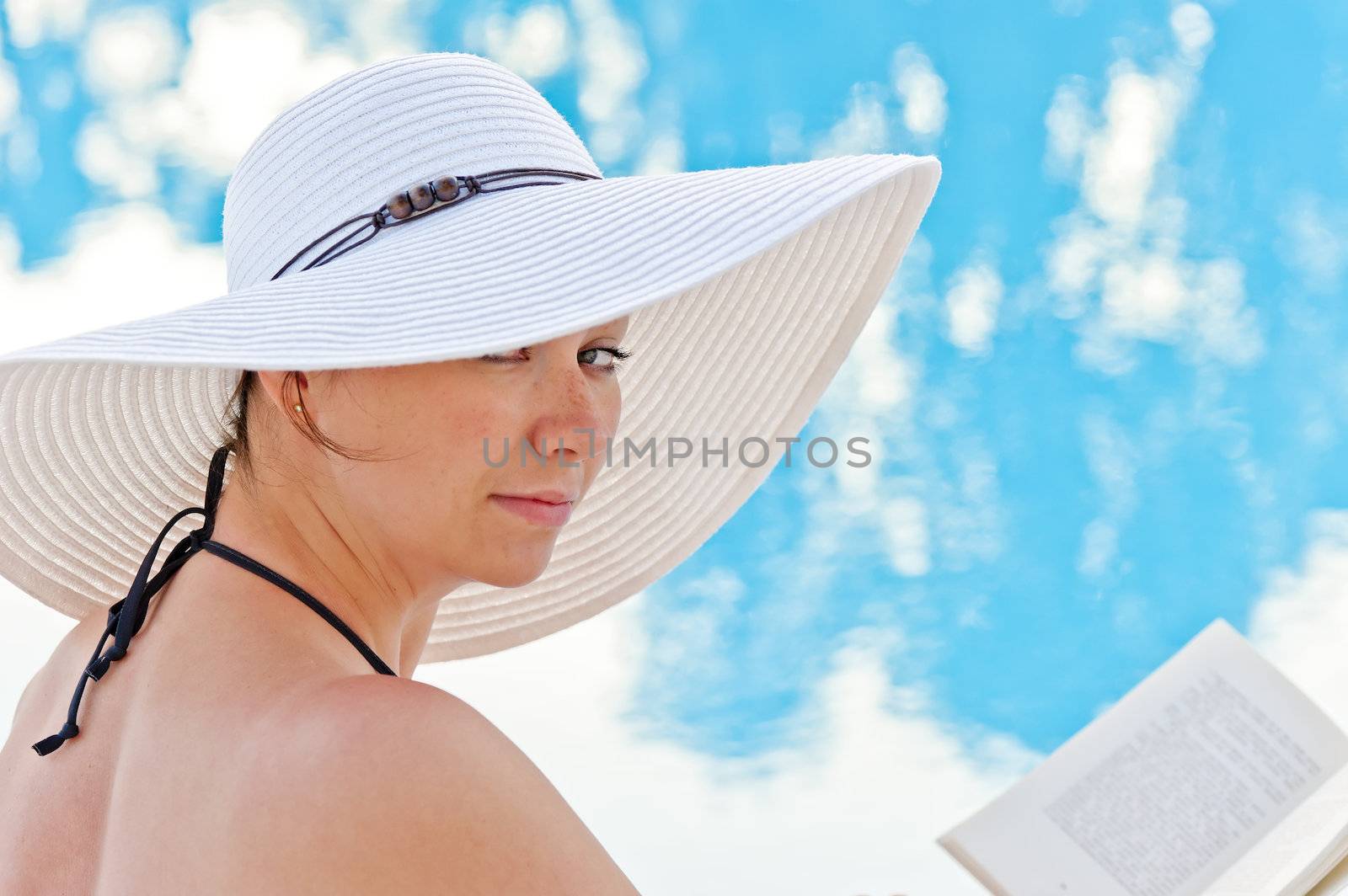 portrait of a beautiful woman sitting with a book by the pool