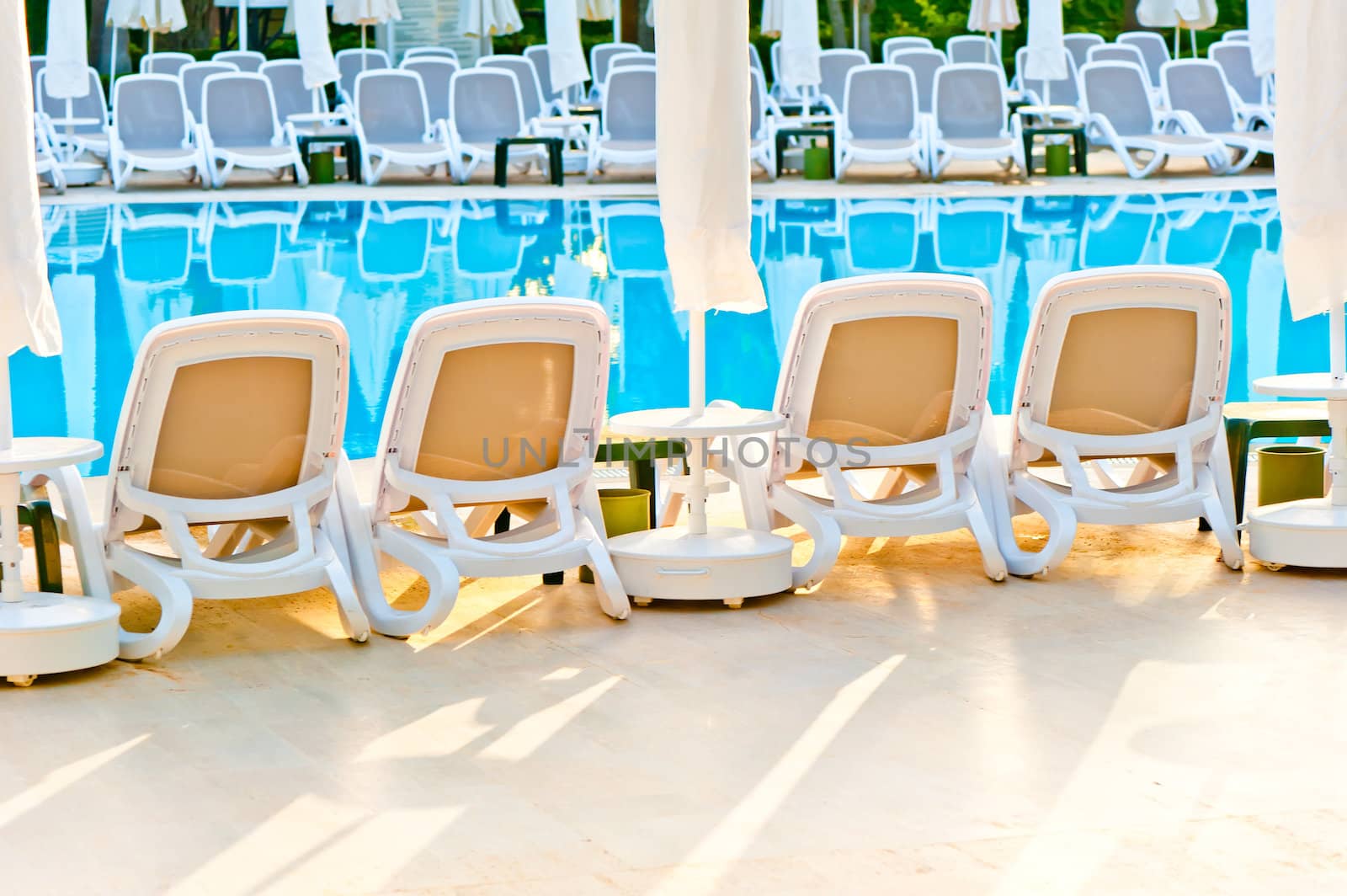 empty chairs stand around the pool at the hotel by kosmsos111