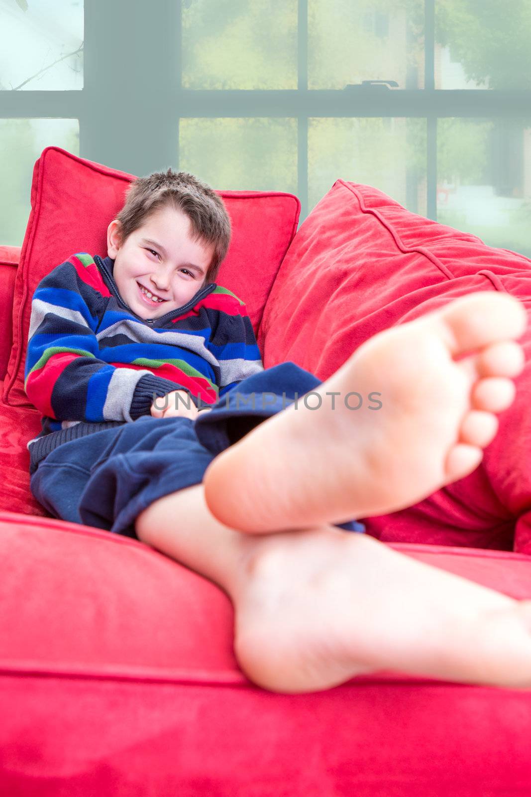 Eight years old kid promoting a feeling of positive on the red couch