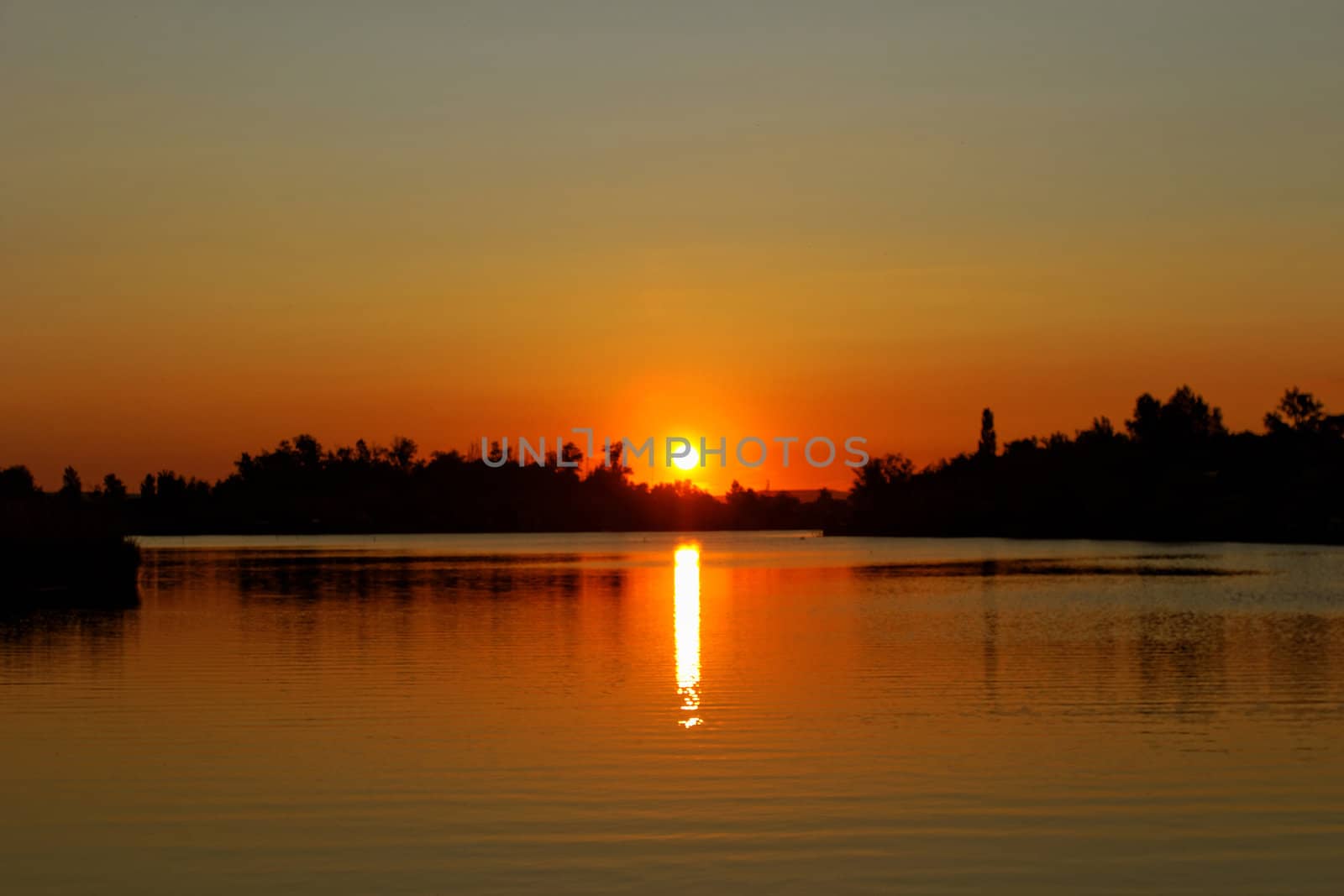 Colorful sunset over tranquil water surface.