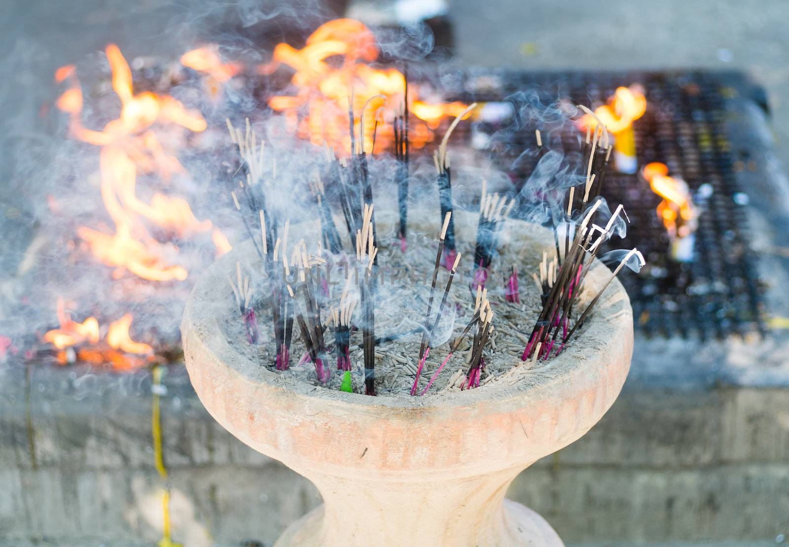 incense sticks burning in pot with fire in background