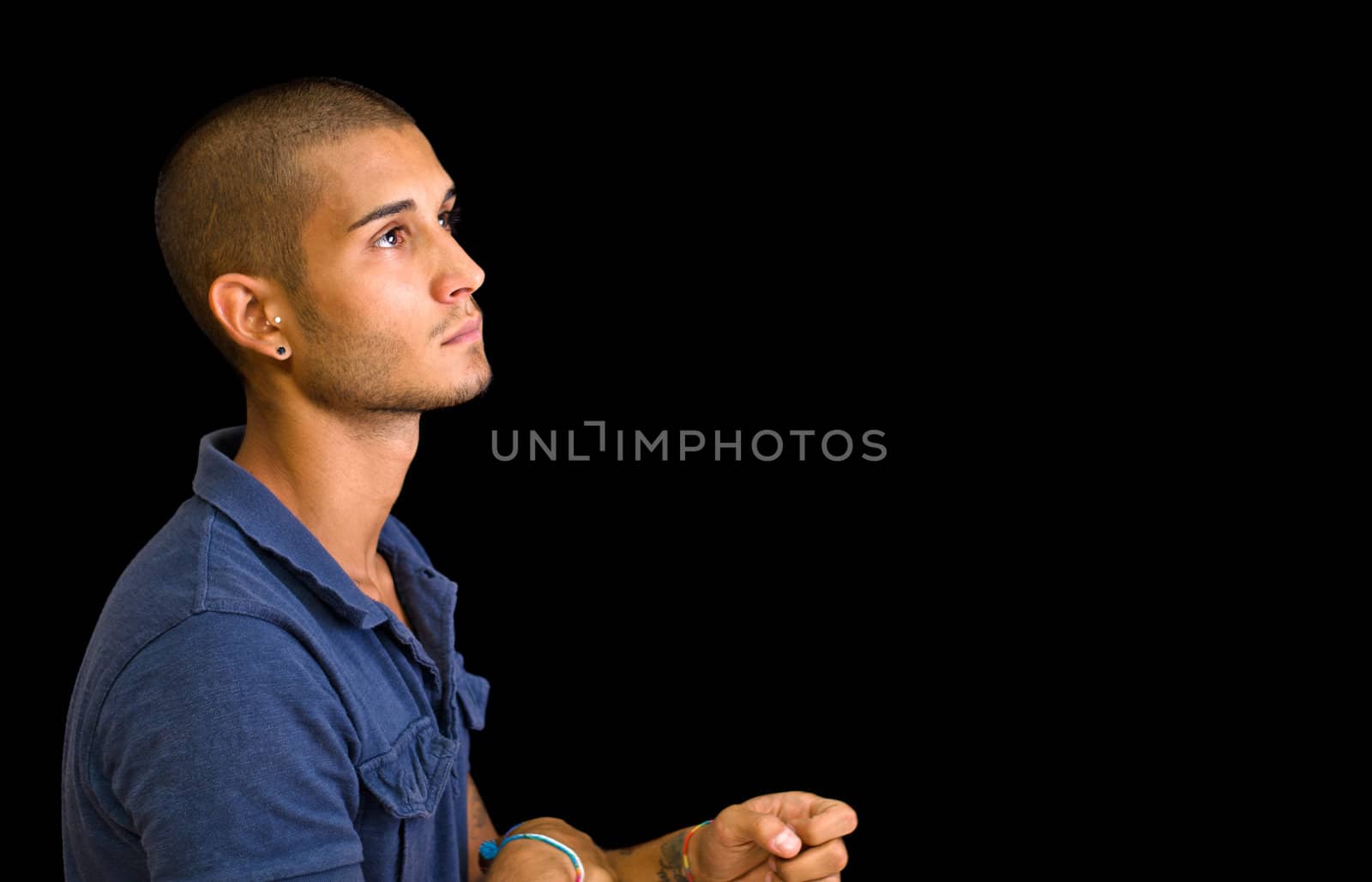 Attractive young man, side view, looking up, isolated on black background