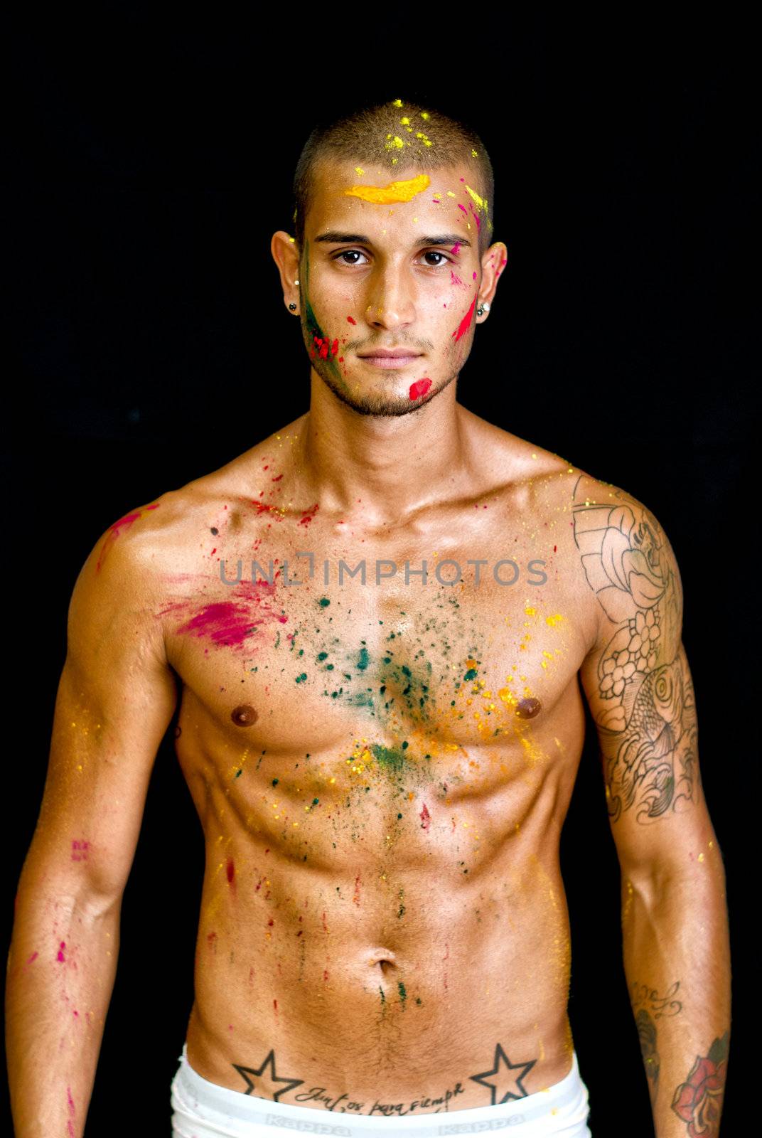 Attractive young man shirtless, skin painted all over with bright Honi  colors