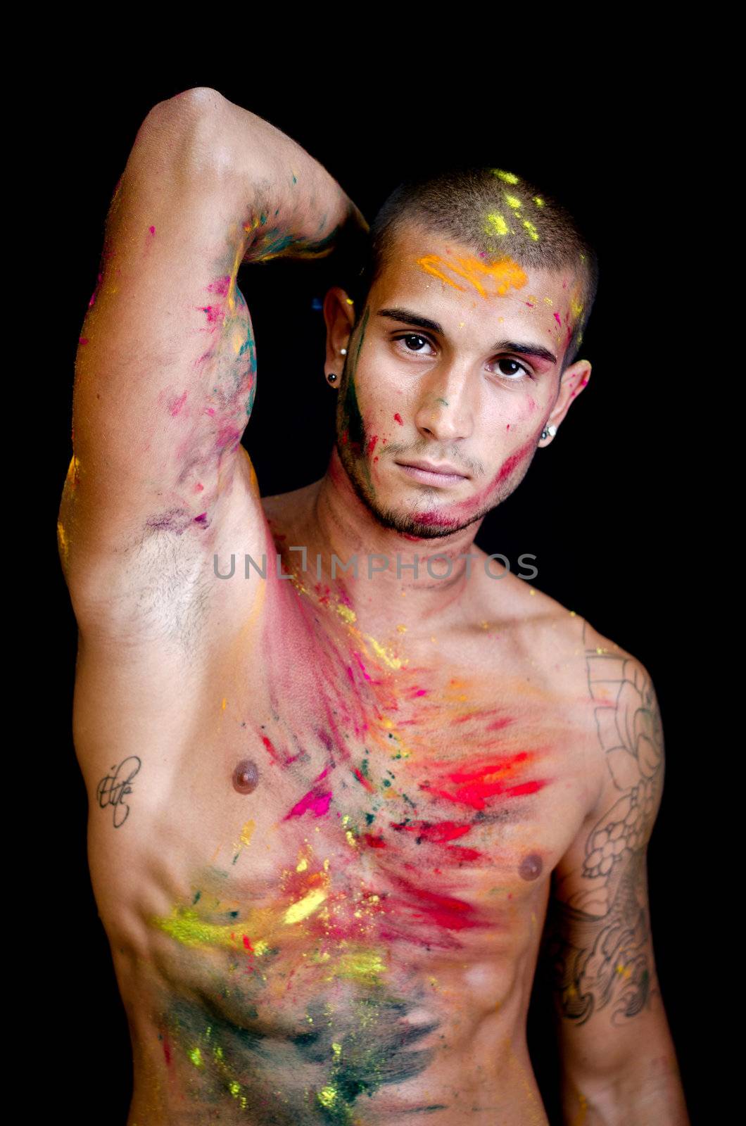 Attractive young man shirtless, skin painted all over with bright colors, arm up and hand behind his head
