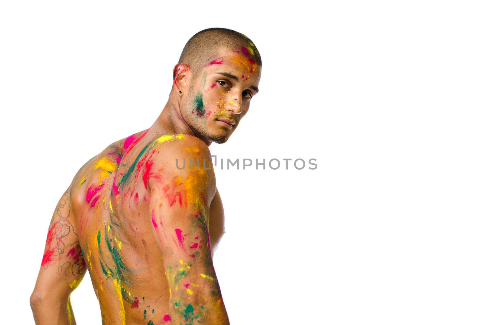 Attractive young man shirtless, skin painted all over with bright colors seen from behind