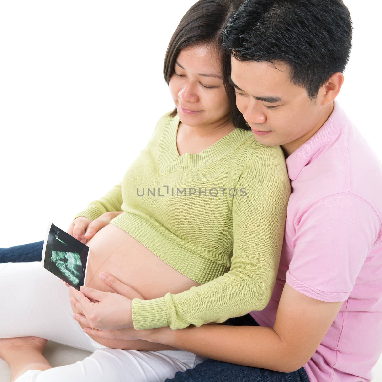 Asian Pregnant couple looking at ultrasound scan photo of unborn child