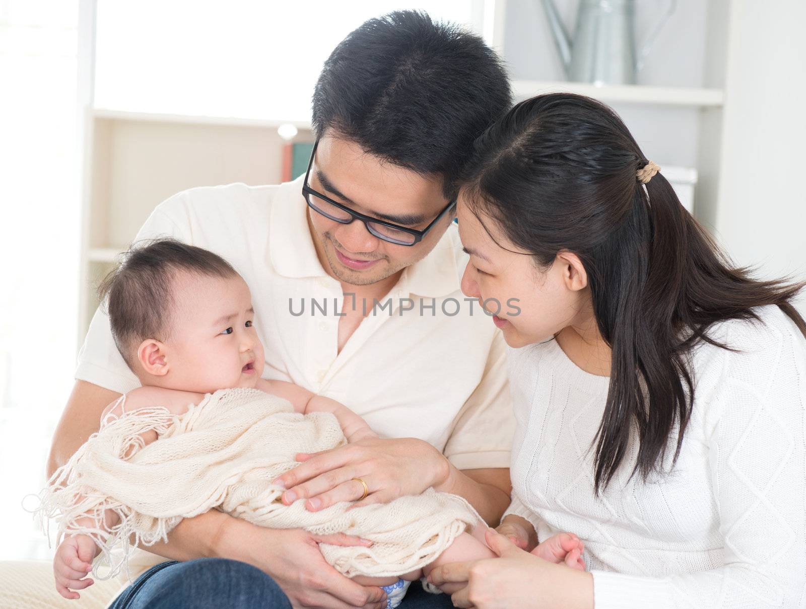 Asian parents pampering six months old baby girl at home.