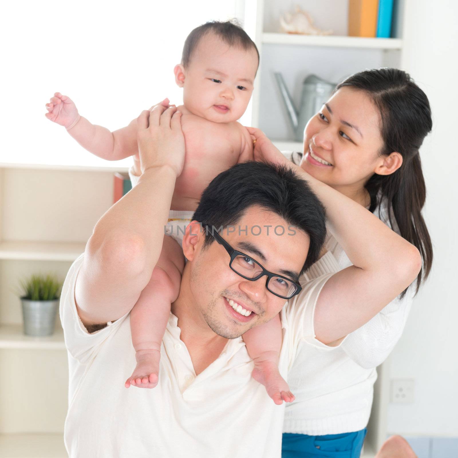 Portrait of Asian parents and six months old baby girl playing at home.