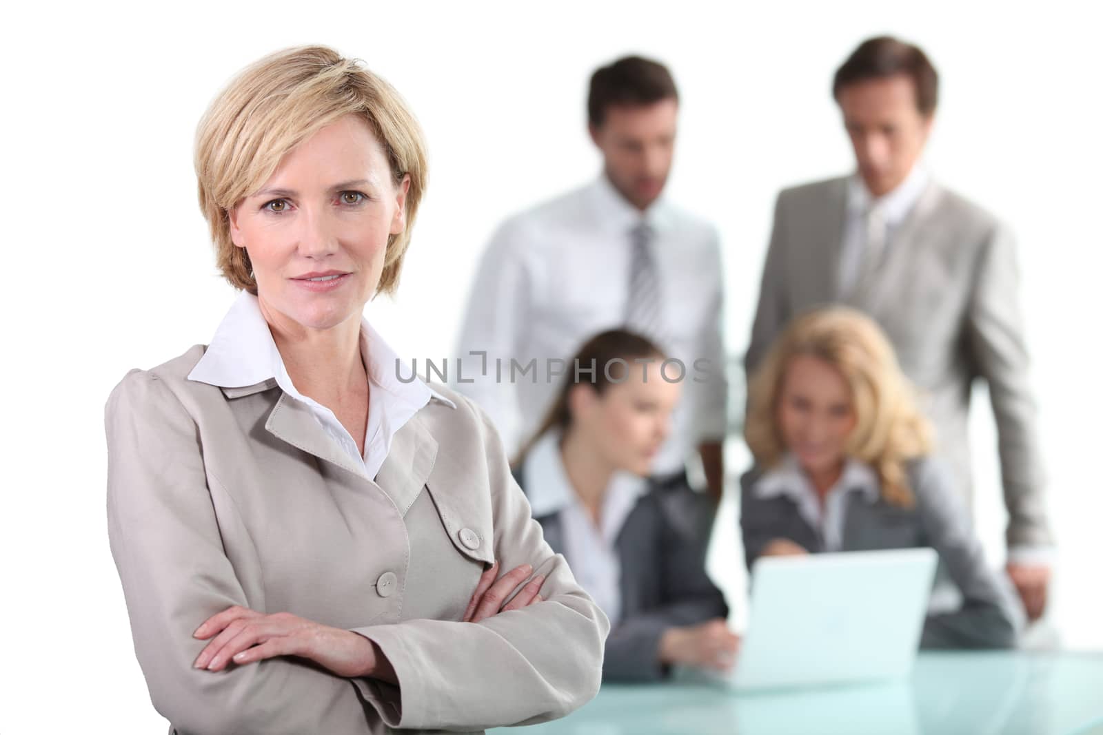 Blond businesswoman with colleagues in background by phovoir