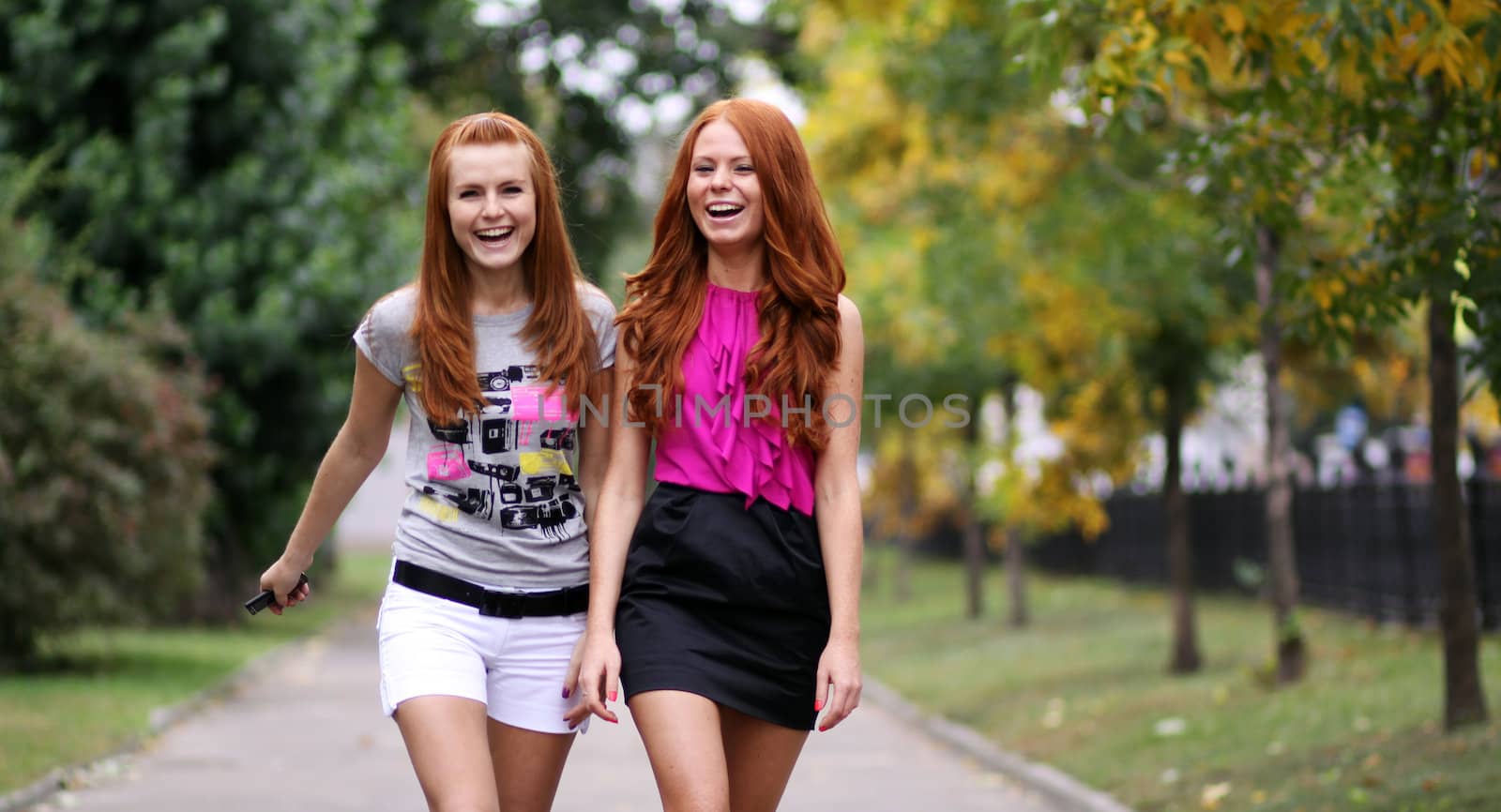 Happy two young women in autumn city by andersonrise