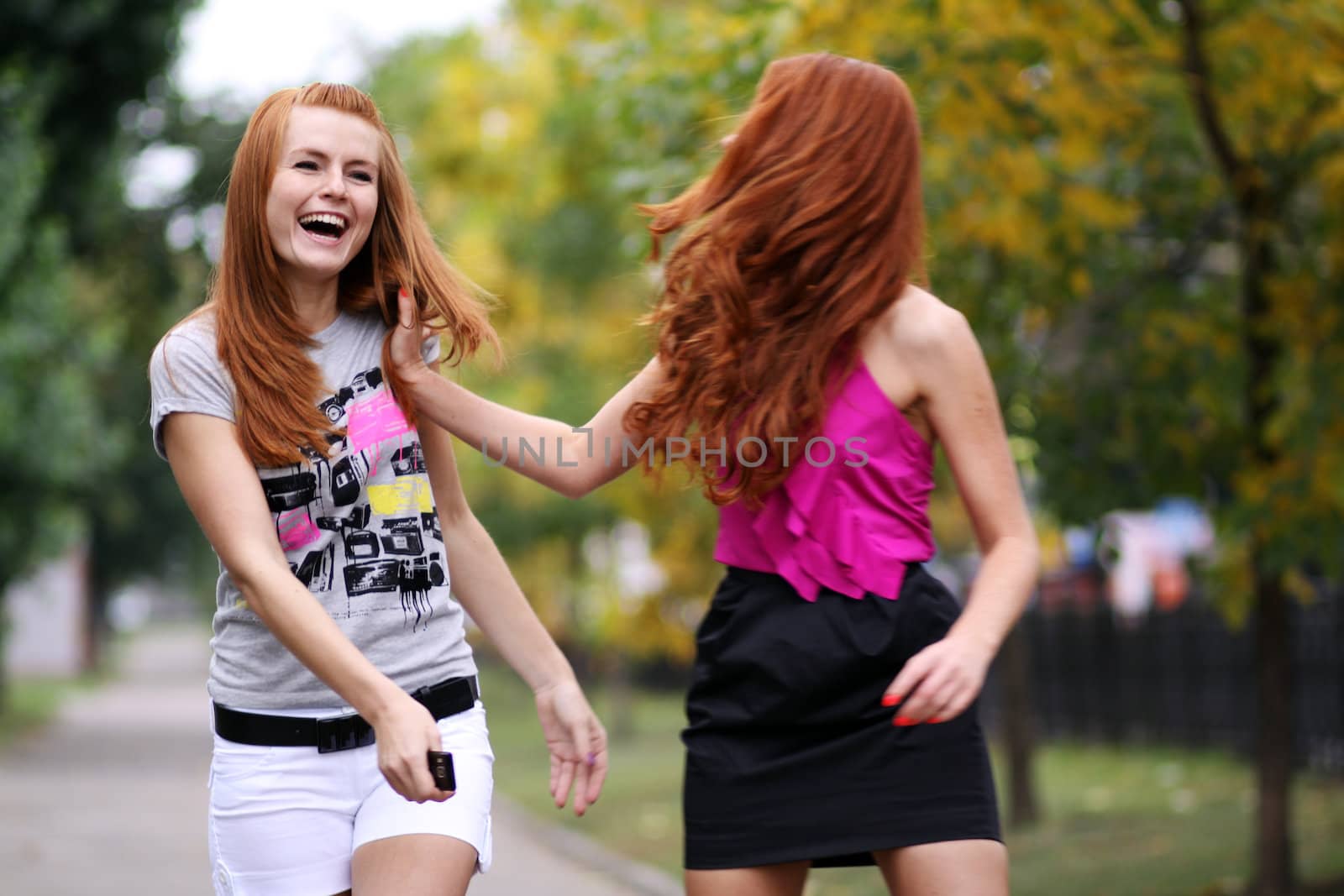 Happy two young women in autumn city by andersonrise