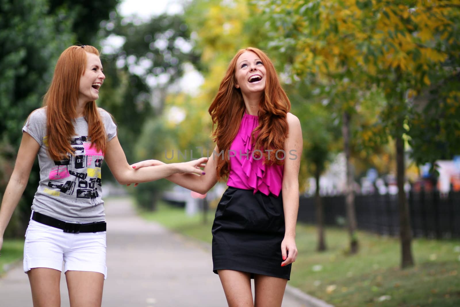 Happy two young women in autumn city by andersonrise