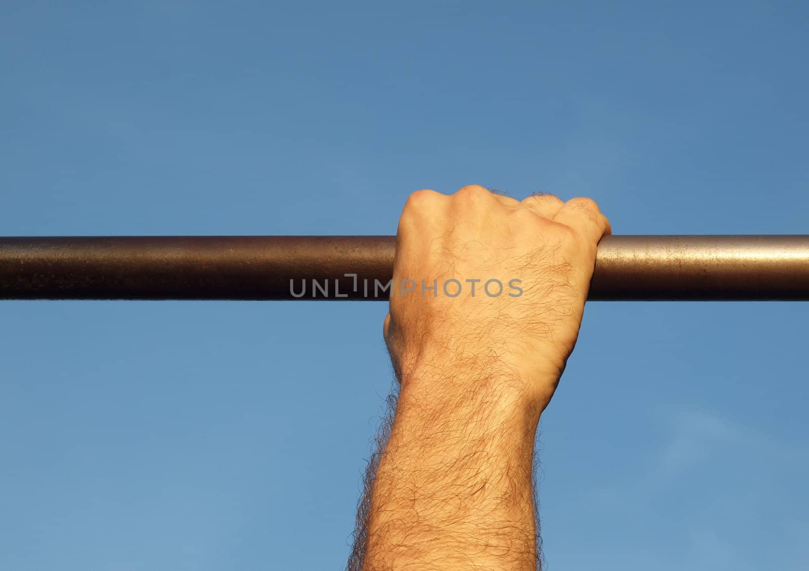 Hand on a crossbeam on a background of the blue sky     