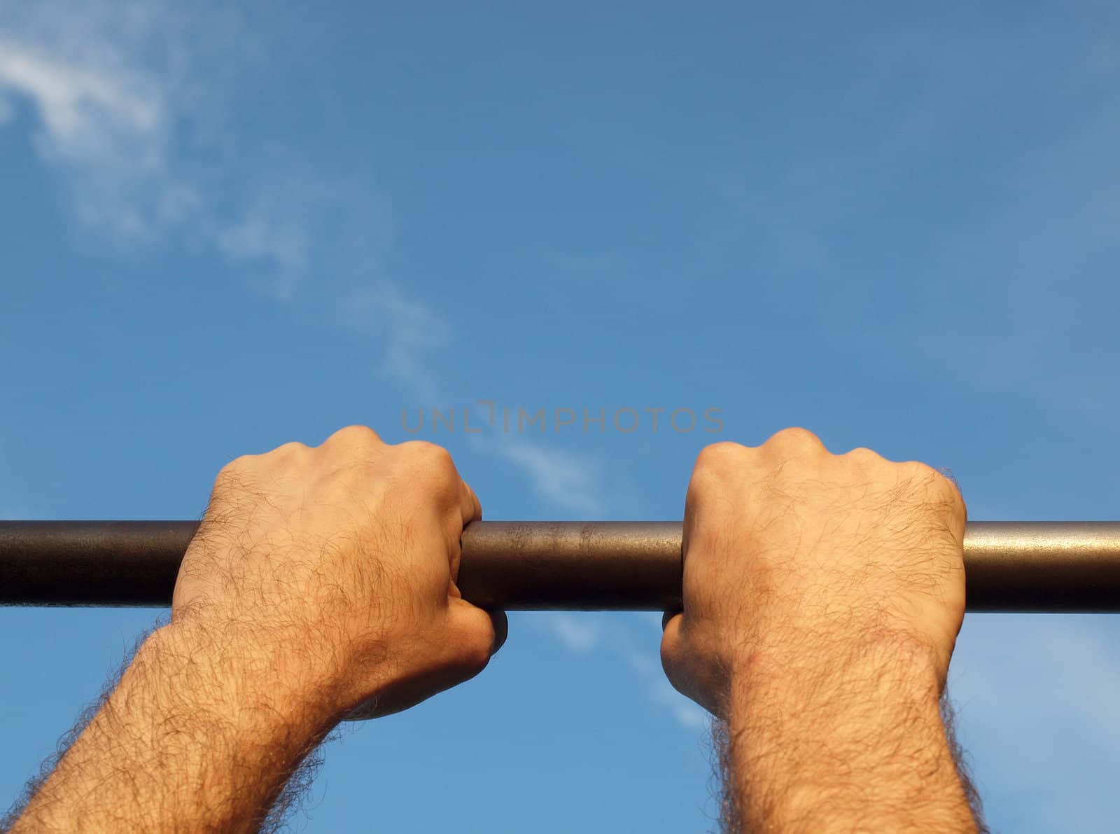Hand on a crossbeam on a background of the blue sky  