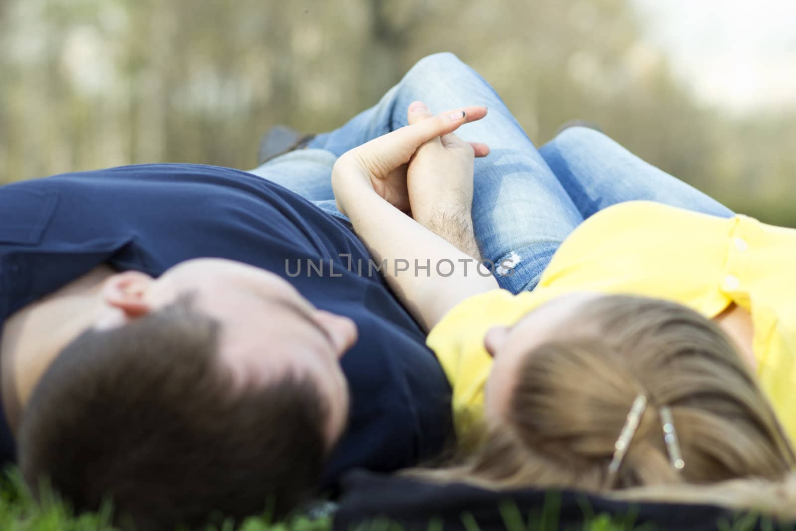 Top view of couple lying on the grass with heads together