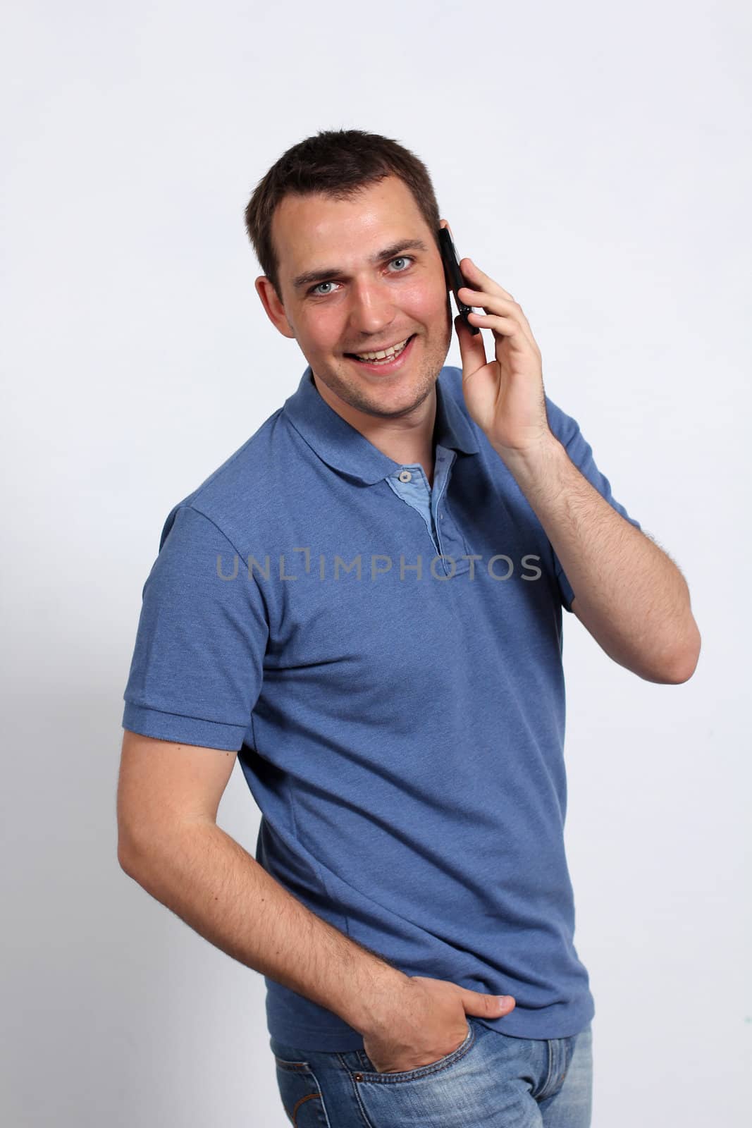 Smiling young man on his mobile phone against a white background