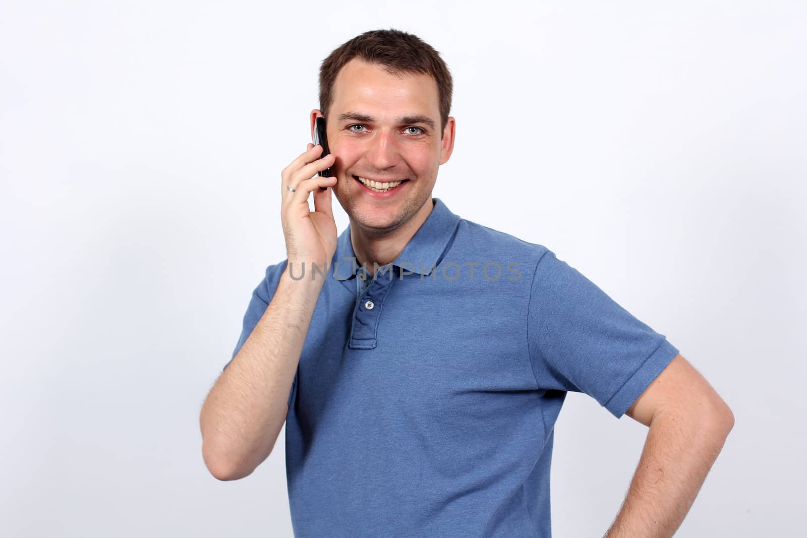 Smiling young man on his mobile phone against a white background